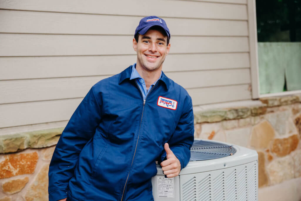 hvac technician leaning on outdoor unit