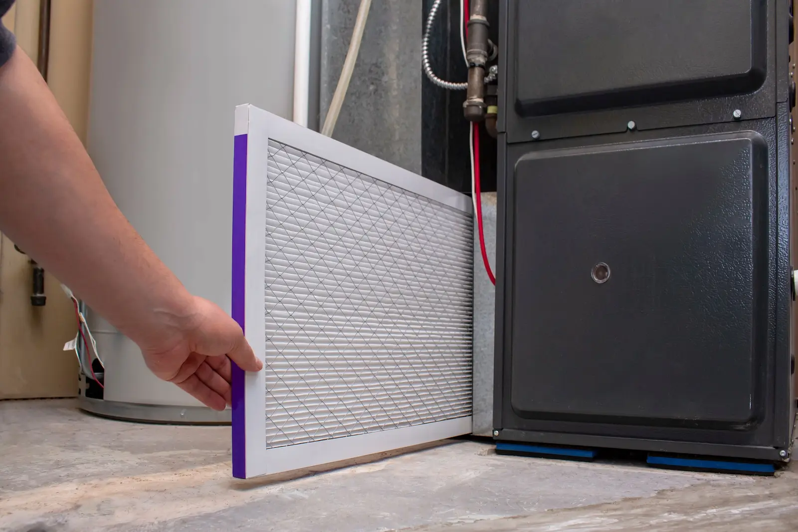 Technician inserting clean air filter into furnace.