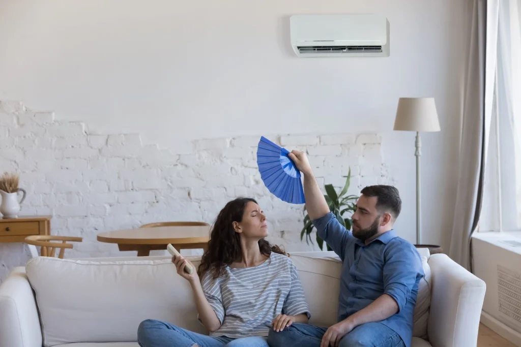 Couple fanning each other inside home in Texas with broken air conditioner.