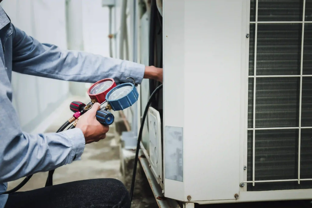 HVAC technician using pressure gauge to perform AC tune-up.