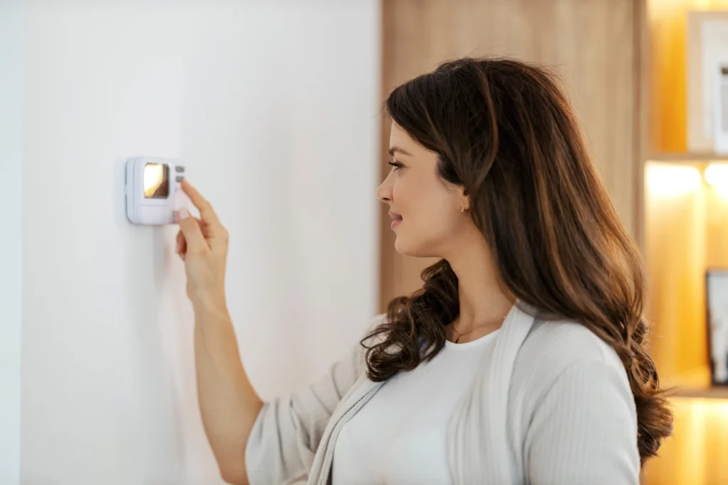 Woman in West Austin home adjusting thermostat to save energy in the summer.