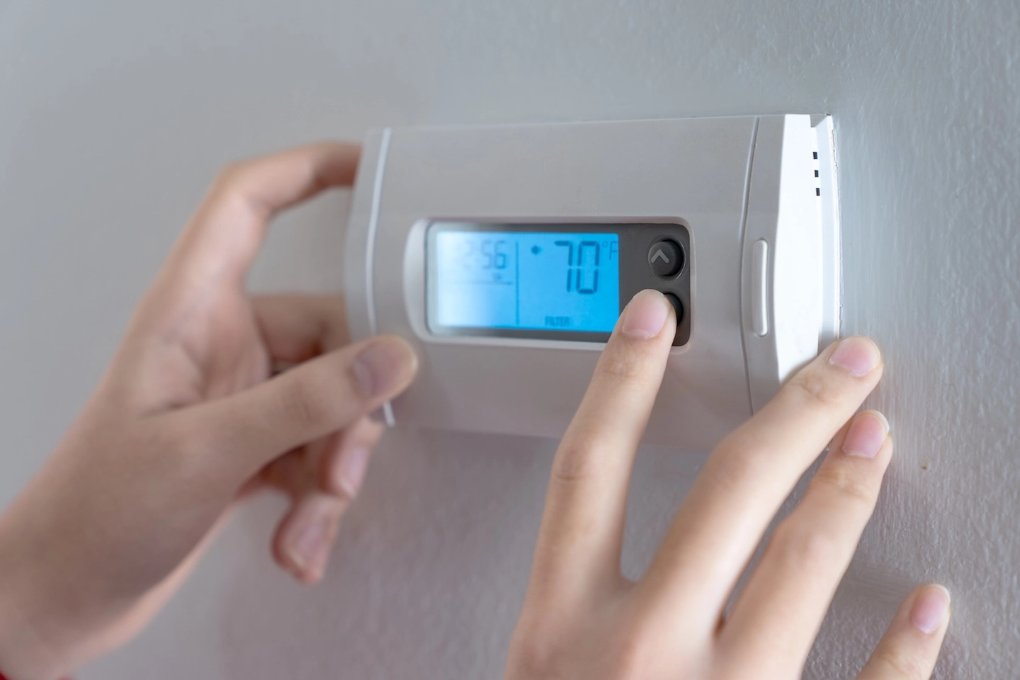 Homeowner adjusting a thermostat to begin heating their home. 