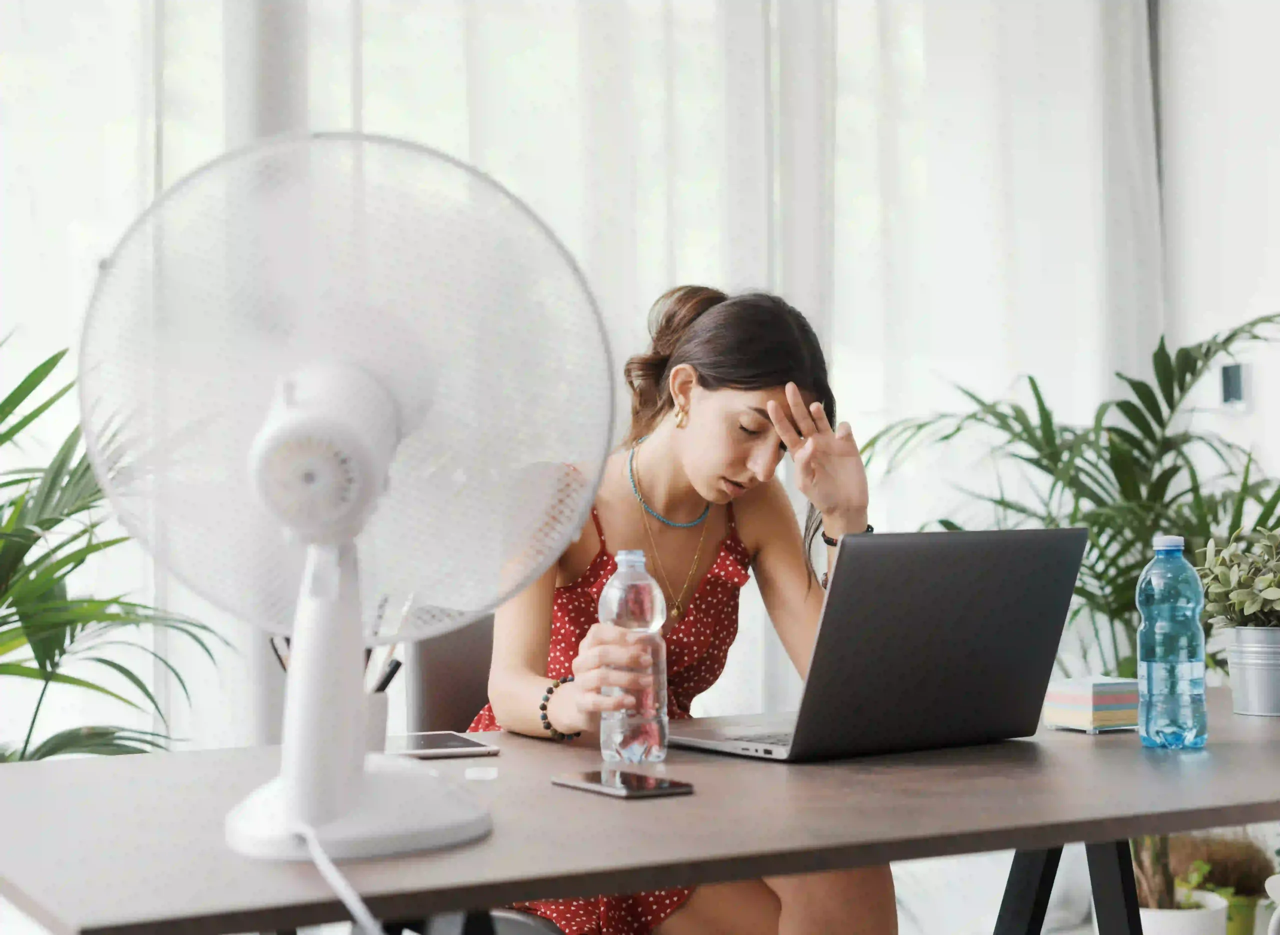 Woman using a fan to cool herself while her AC is out of action.