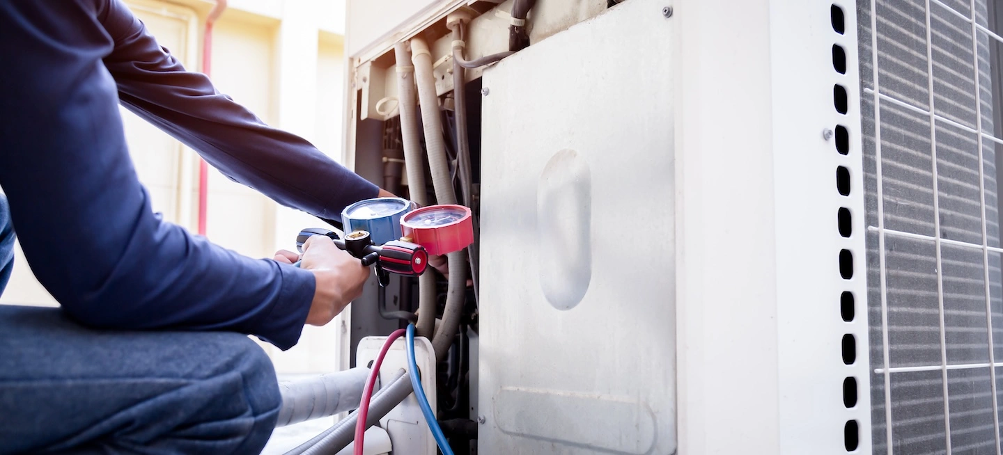 HVAC technician checking on an outdoor heat pump unit