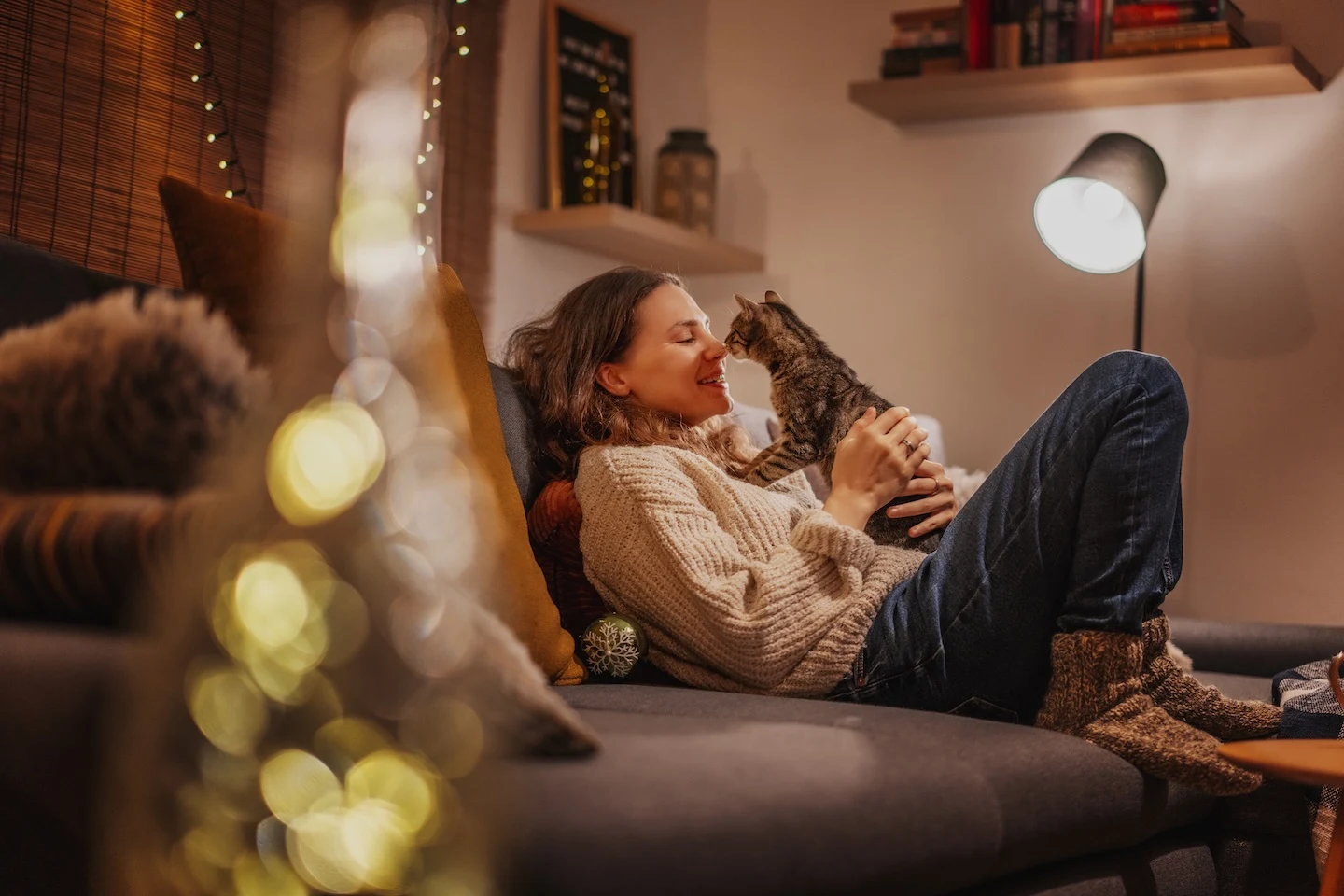 Woman relaxing at home with her cat during cold weather season